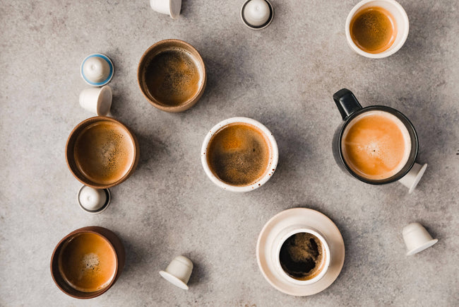 Coffee pods and full cups of coffee, made with specialty coffee pods, shot from above.