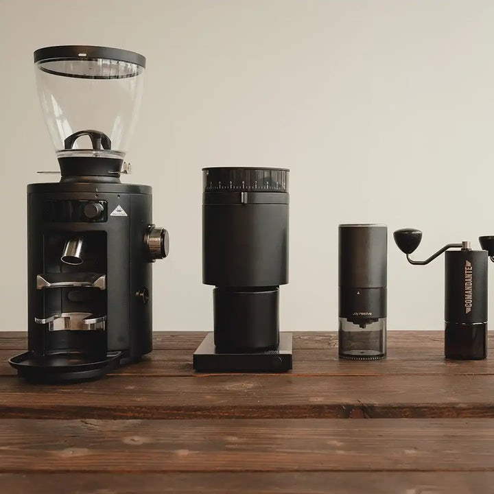 4 coffee grinders lined up on a table